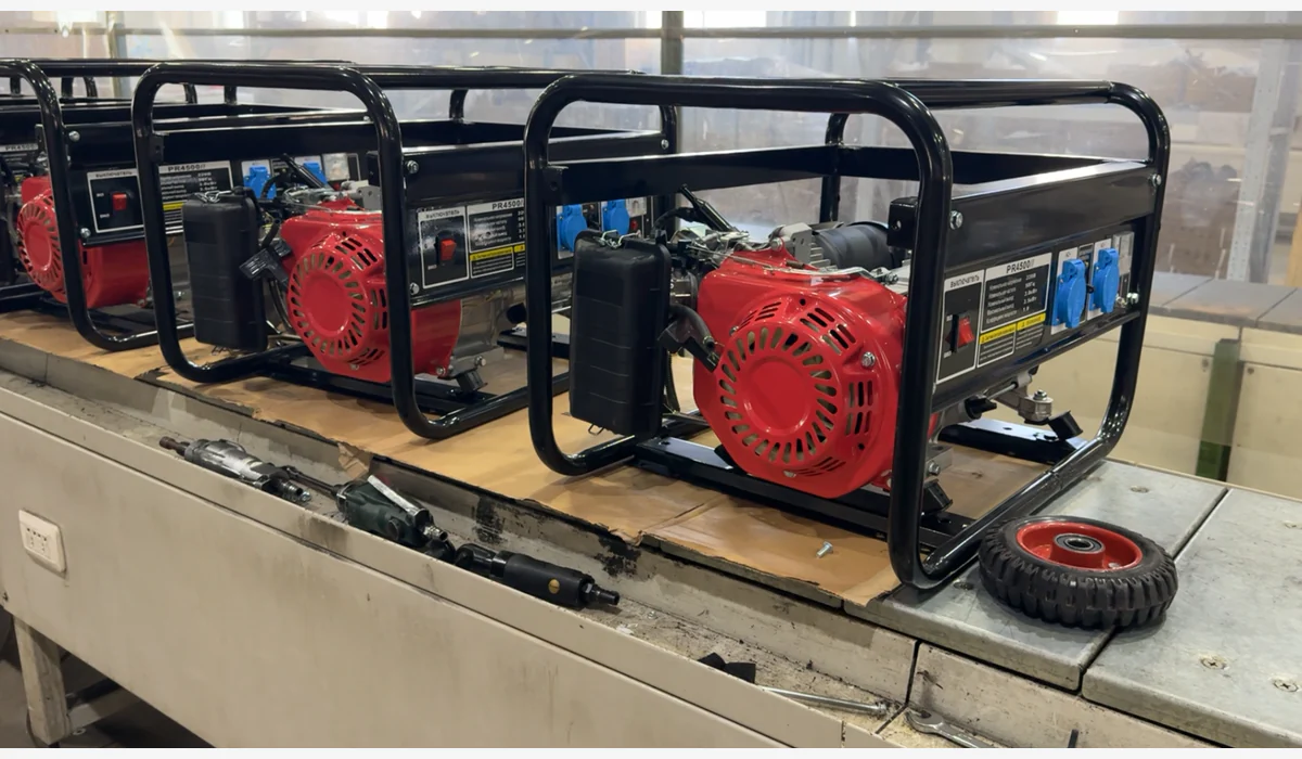 Two open-frame generator units on a workbench beside a loose wheel and assembly tools