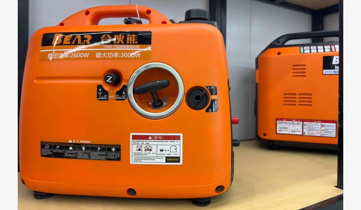 Orange generator enclosure with brand, model, power and safety labels visible beside a second unit