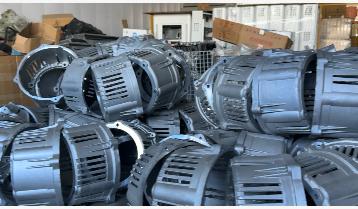 Multiple gray alternator housings and covers stacked together in a workshop area