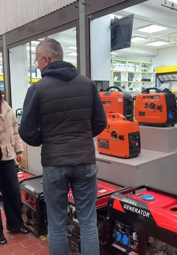 Buyer comparing portable generators at an overseas retail display